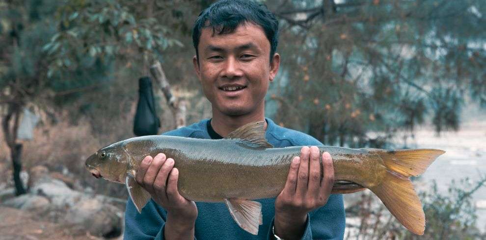 Bhutanese man carrying Mahseer Fish, During Fly Fishing Tour Punakha in Bhutan